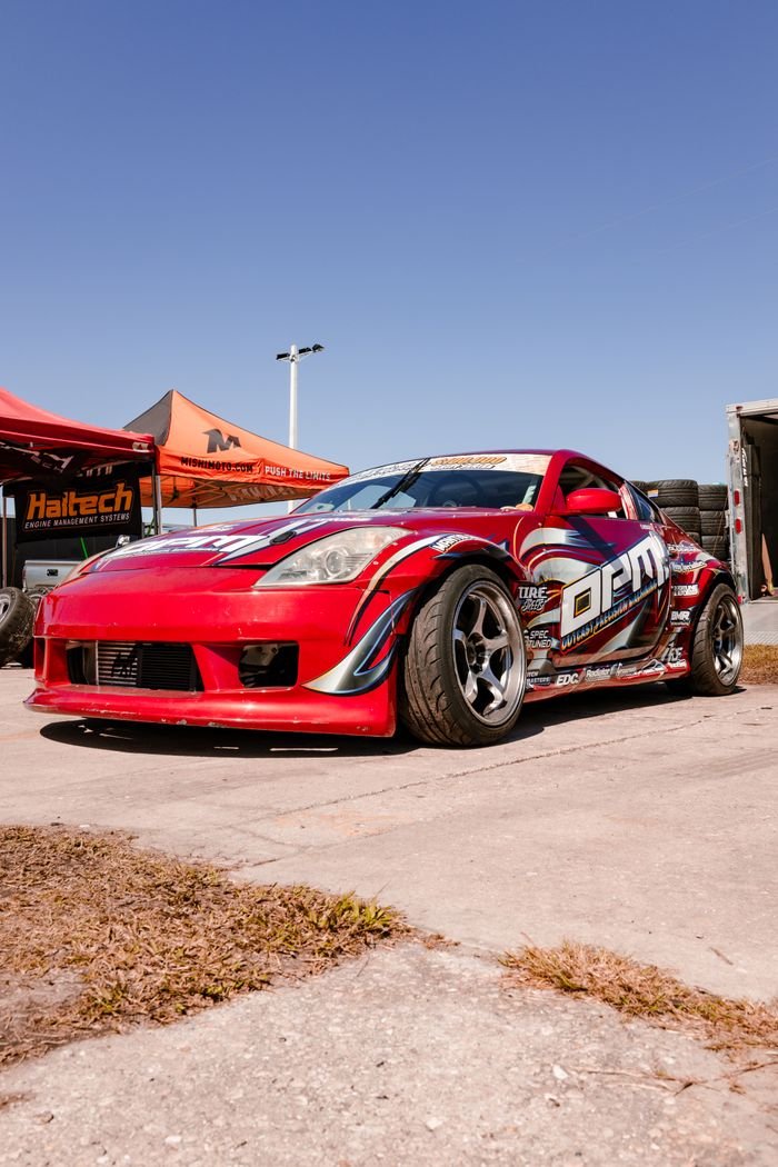 Dynamic Nissan 350Z showcased at a motorsport drifting event under clear blue skies.