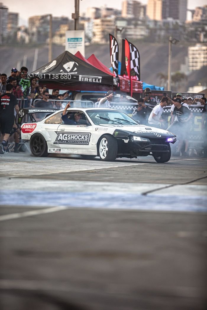 social-feed-img-05 Dynamic drift car in action during lively auto racing event with spectators