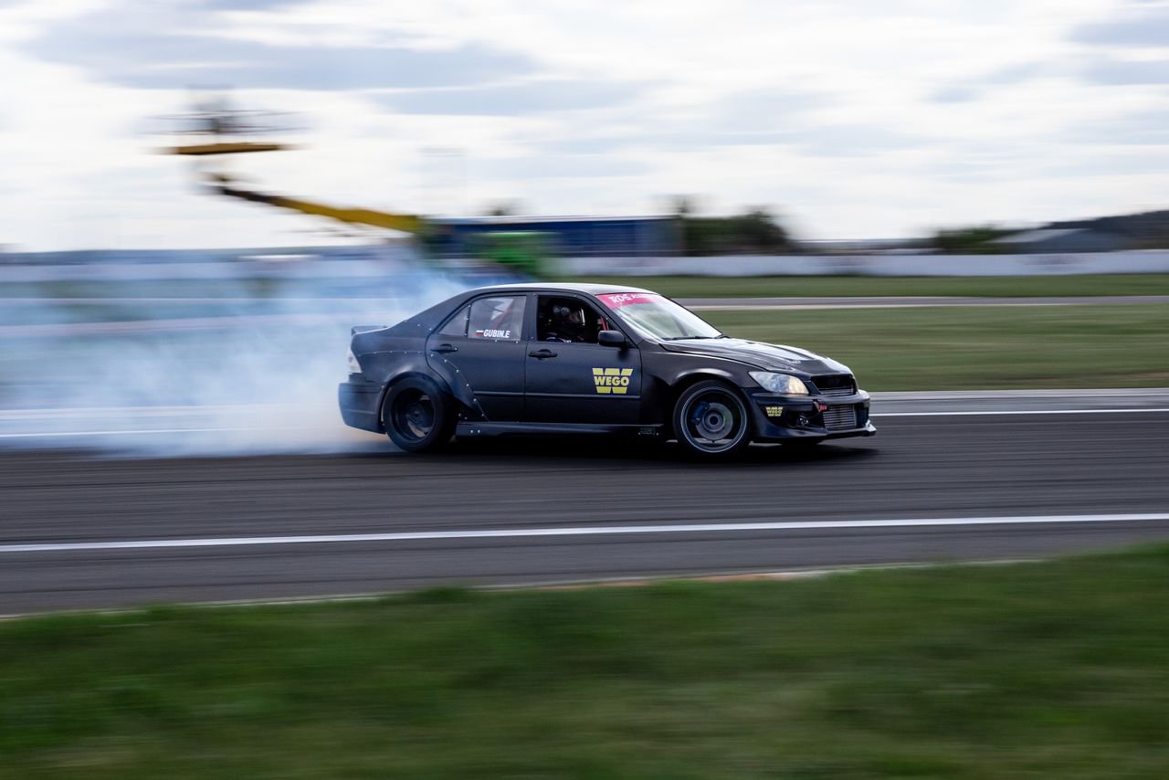 social-feed-img-04 Dynamic shot of a car drifting on a racetrack with smoke trails and blurred motion.