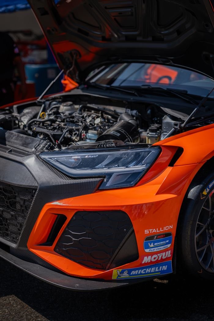 Detailed view of an orange race car with open hood at a Lexington, Ohio race event.